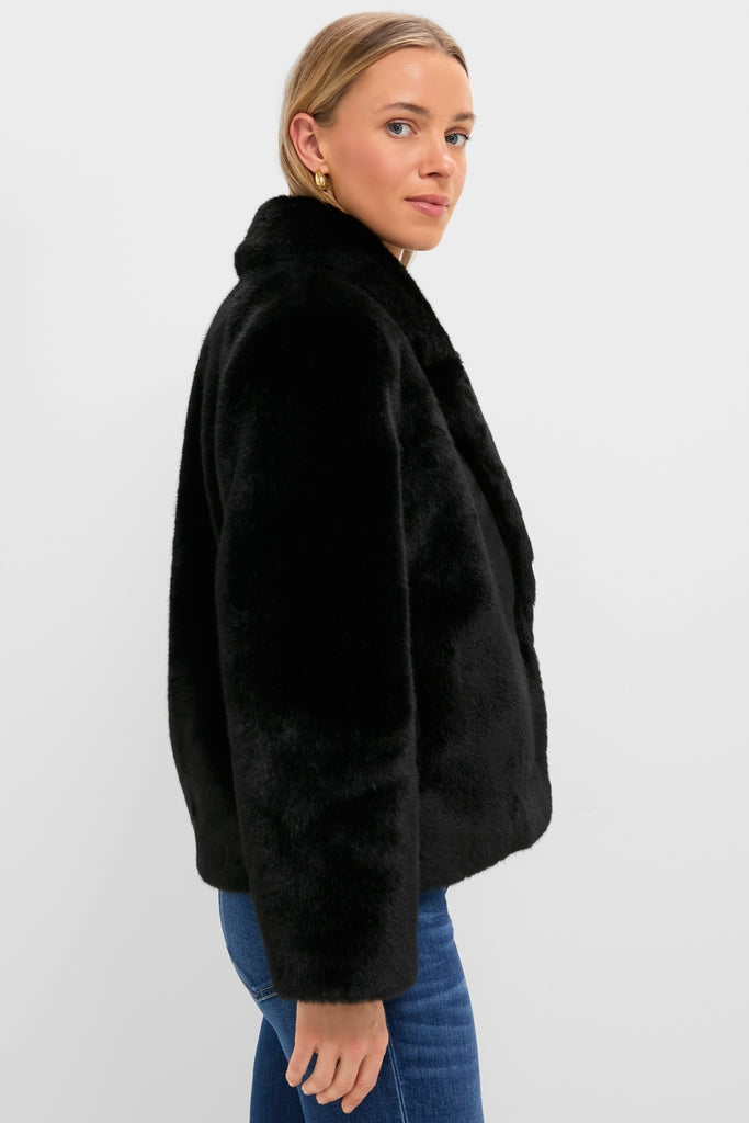 Woman in profile wearing the classic Black Faux Fur Taos Jacket with blue jeans and a gold hoop earring, embodying an effortless, high-end style.