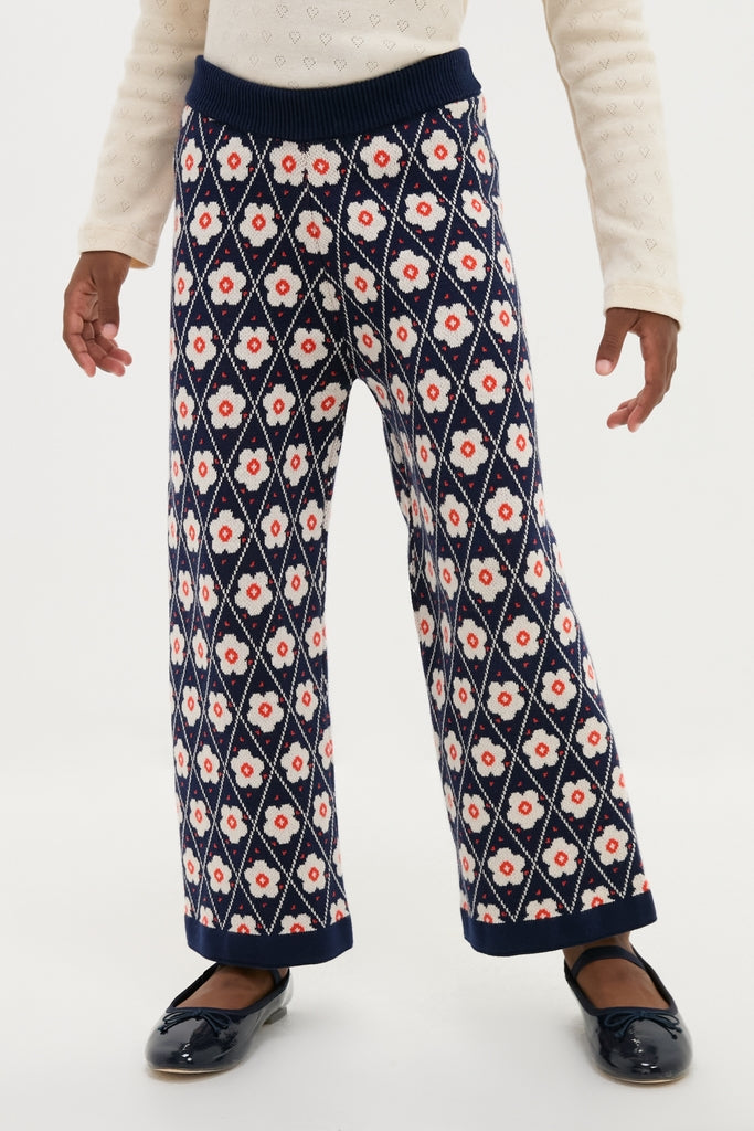 Child wearing Navy Flower Mathilda Pants with diamond-grid floral pattern, elastic waistband, and ballet flats. Classic, effortless style combining comfort and fun for a high-end look.