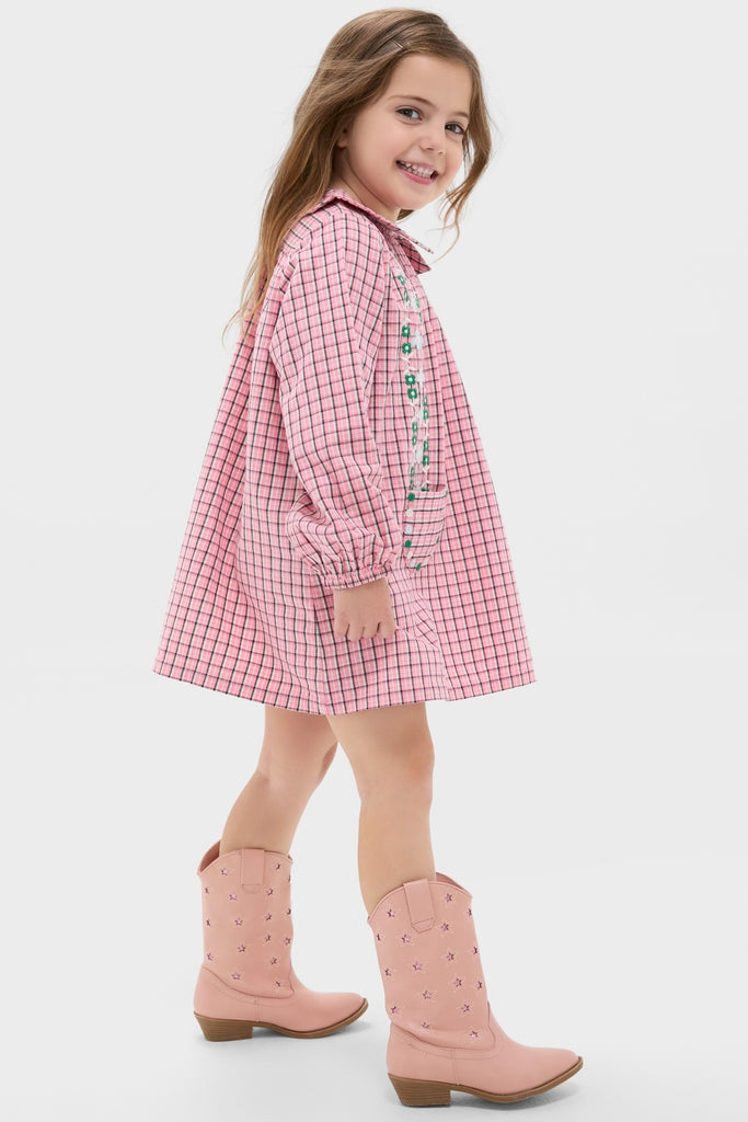 Young girl in a Pink Check Gatsby Dress, featuring playful embroidery and pockets, paired with stylish pink cowboy boots, capturing a classic and effortless charm.