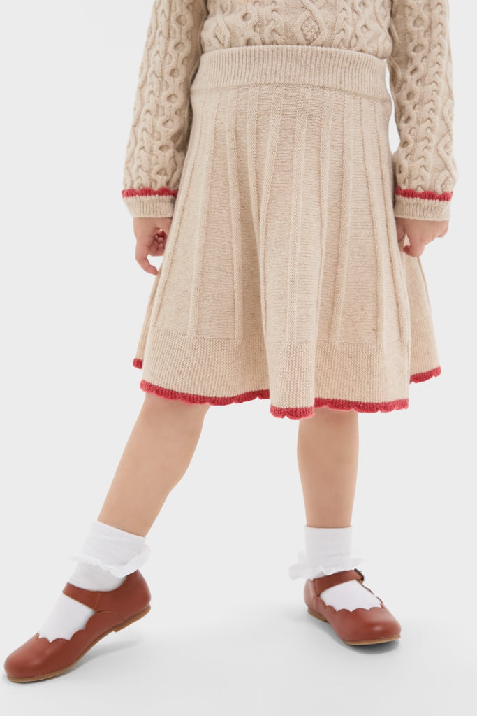 Child wearing the Sienna Skirt, a classic, high-end pleated knit with red scallop trim, paired with a matching sweater, embodying effortless, fun vintage charm.