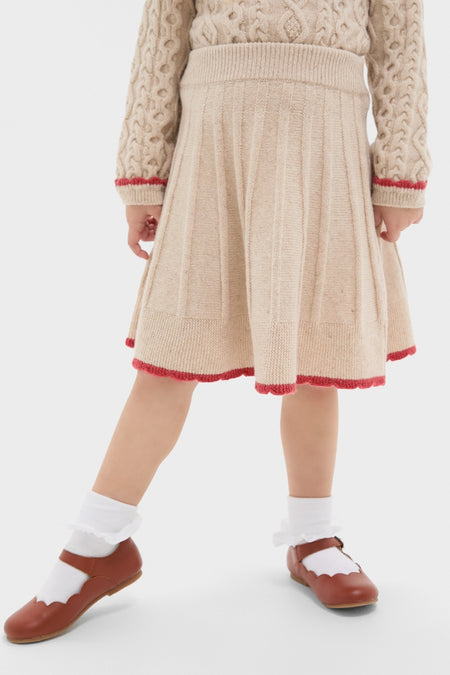 Child wearing the Sienna Skirt, a classic, high-end pleated knit with red scallop trim, paired with a matching sweater, embodying effortless, fun vintage charm.