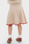 Child in cream Sienna Skirt with classic pleats, red scalloped trim, ruffled socks, and Mary Jane shoes. Effortless, high-end vintage charm for fun, cool style.