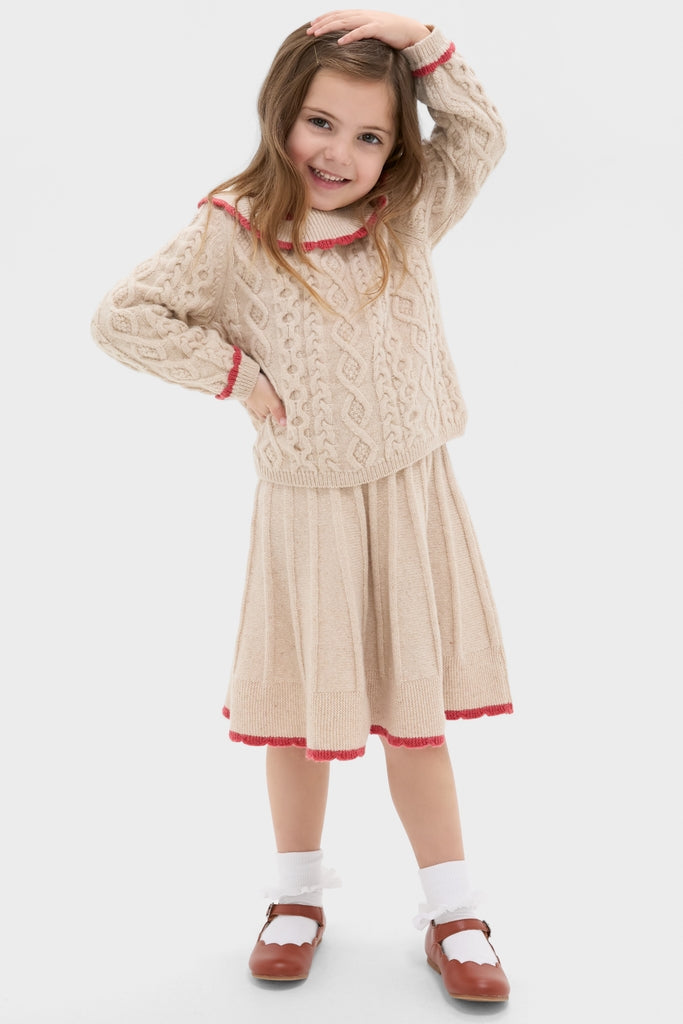 Young girl in a classic, high-end Sienna Skirt with pleats and red scallop trim, embodying effortless fun and vintage charm.