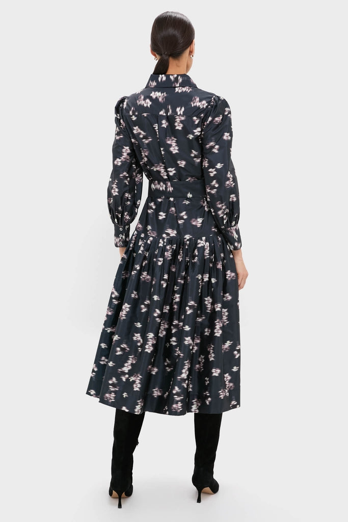 Rear view of a woman in the classic, effortless Lebombo Black Nora Midi Dress, showcasing its fitted bodice, full skirt, and knee-high boots for a fun, high-end look.