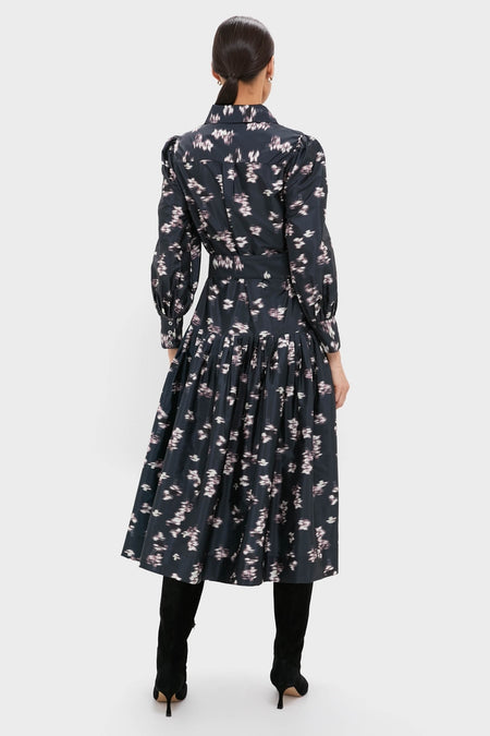 Rear view of a woman in the classic, effortless Lebombo Black Nora Midi Dress, showcasing its fitted bodice, full skirt, and knee-high boots for a fun, high-end look.