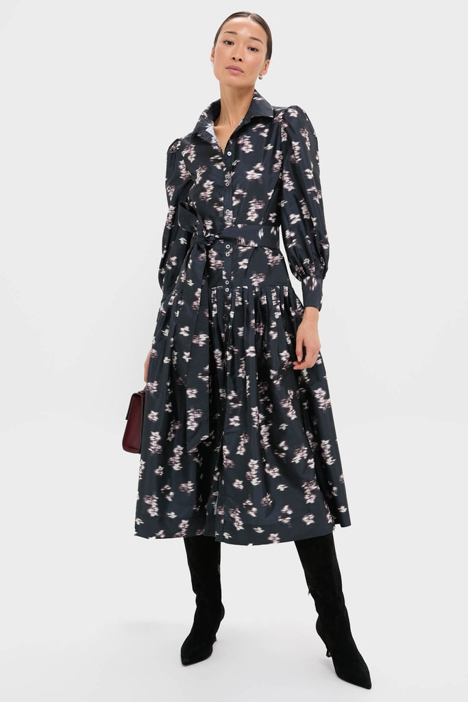 Lebombo Black Nora Midi Dress: A classic, effortless midi dress with a floral print, puffed sleeves, and self-tie belt, styled with knee-high boots and a burgundy handbag.