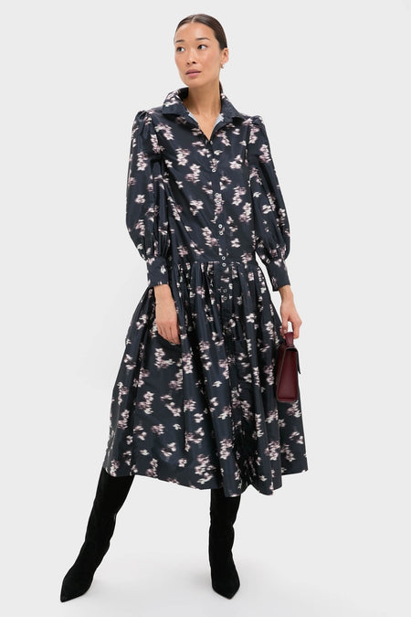 Woman in classic, high-end Lebombo Black Nora Midi Dress with floral print, styled with knee-high boots and a burgundy handbag, exuding an effortless, fun elegance.