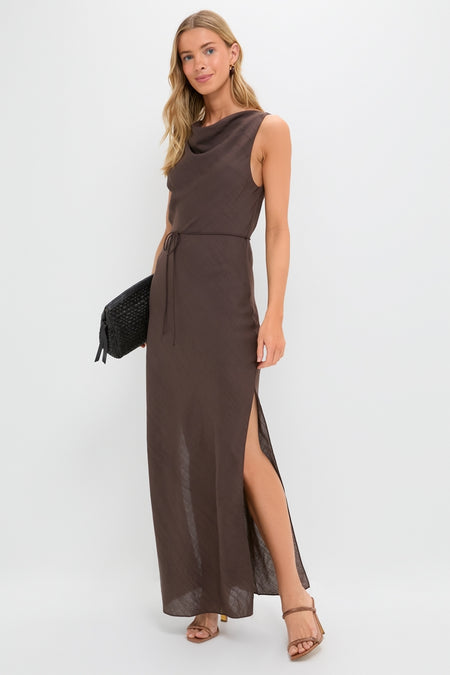 Model wearing the Chocolate Serine Maxi Dress featuring a classic cowl neckline and high side slit. Paired with tan block-heeled sandals and a black clutch, exuding effortless, high-end style.