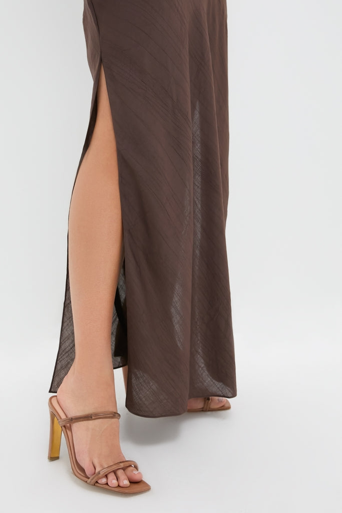 Chocolate Serine Maxi Dress featuring a high side slit, styled with light brown, open-toe strappy sandals. A classic, effortless look exuding fun and high-end elegance.