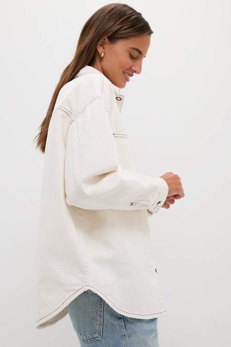 Young woman wearing the classic Natural Bryden Denim Jacket, an oversized off-white shacket, paired with jeans, exuding an effortless and fun high-end style.