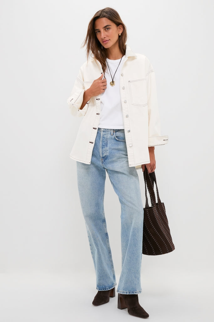 Model wearing the high-end Natural Bryden Denim Jacket with classic seam-stitching, paired effortlessly with light-wash jeans, dark brown ankle boots, and a fun, woven tote.