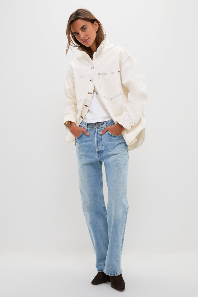 Woman wearing the classic, high-end Natural Bryden Denim Jacket over a white top, paired with light-wash jeans and ankle boots, exuding an effortless and fun style.