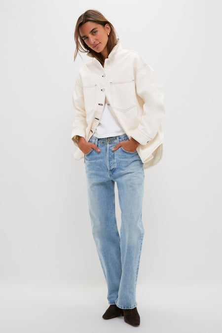 Woman wearing the classic, high-end Natural Bryden Denim Jacket over a white top, paired with light-wash jeans and ankle boots, exuding an effortless and fun style.
