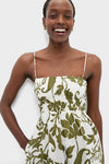 Woman in classic Dahlia Maxi Dress with olive floral print and square neckline, featuring smocked bodice, adjustable straps, and side pockets for an effortless, fun, high-end look.