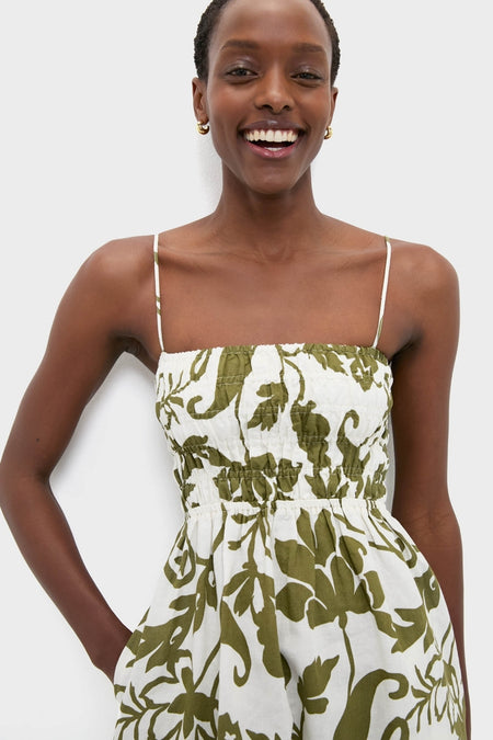 Woman in classic Dahlia Maxi Dress with olive floral print and square neckline, featuring smocked bodice, adjustable straps, and side pockets for an effortless, fun, high-end look.
