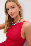 Person wearing Vermillion Lotta Mini Dress with a sleeveless, fitted design, paired with a multicolored beaded necklace and gold hoop earrings, exuding a classic, effortless, high-end look.