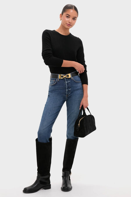 Woman models Black Benni Riding Boots, showcasing their classic knee-high suede and leather design with an effortless gold buckle, embodying fun and high-end style from Stuart Weitzman.