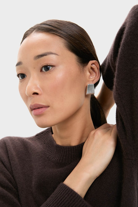 Woman wearing classic Silver Ribbed Earrings with a sculptural, ribbed design, adding effortless elegance and high-end polish to her look.
