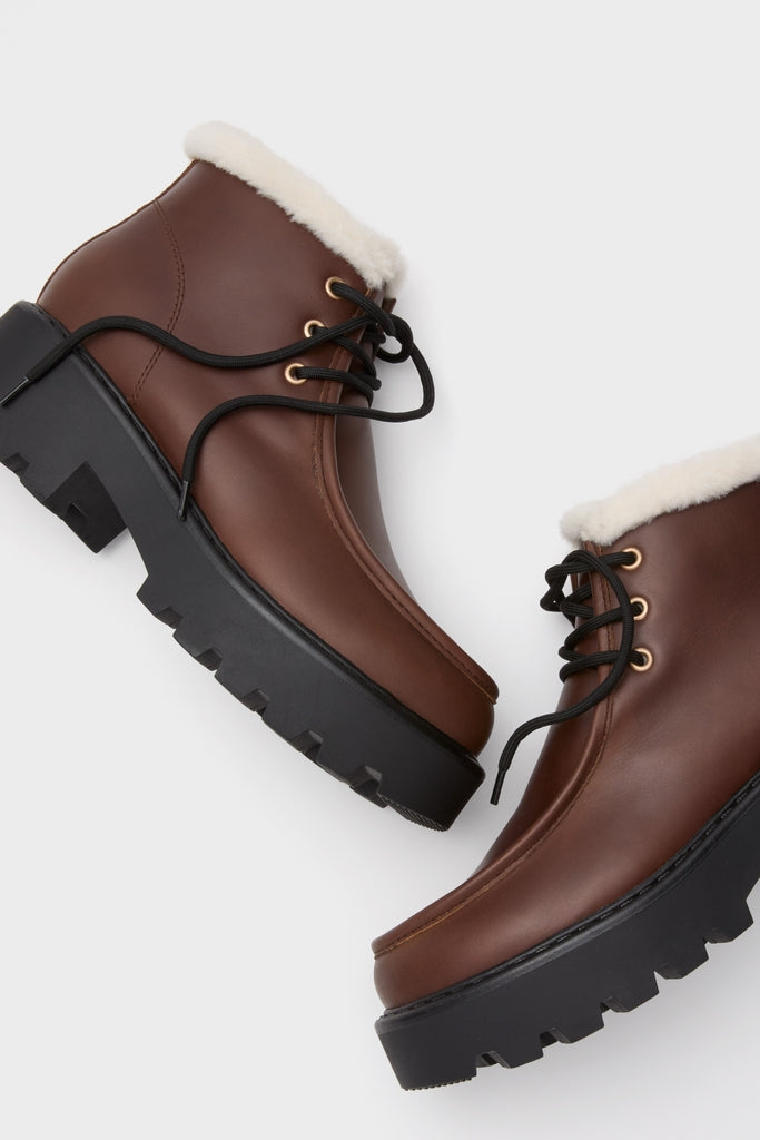 Dark Brown Percy Boots: Classic ankle-height lace-up boots with gold-tone eyelets, lug soles, and sherpa lining. Effortless style blends fun, high-end design with functional comfort.