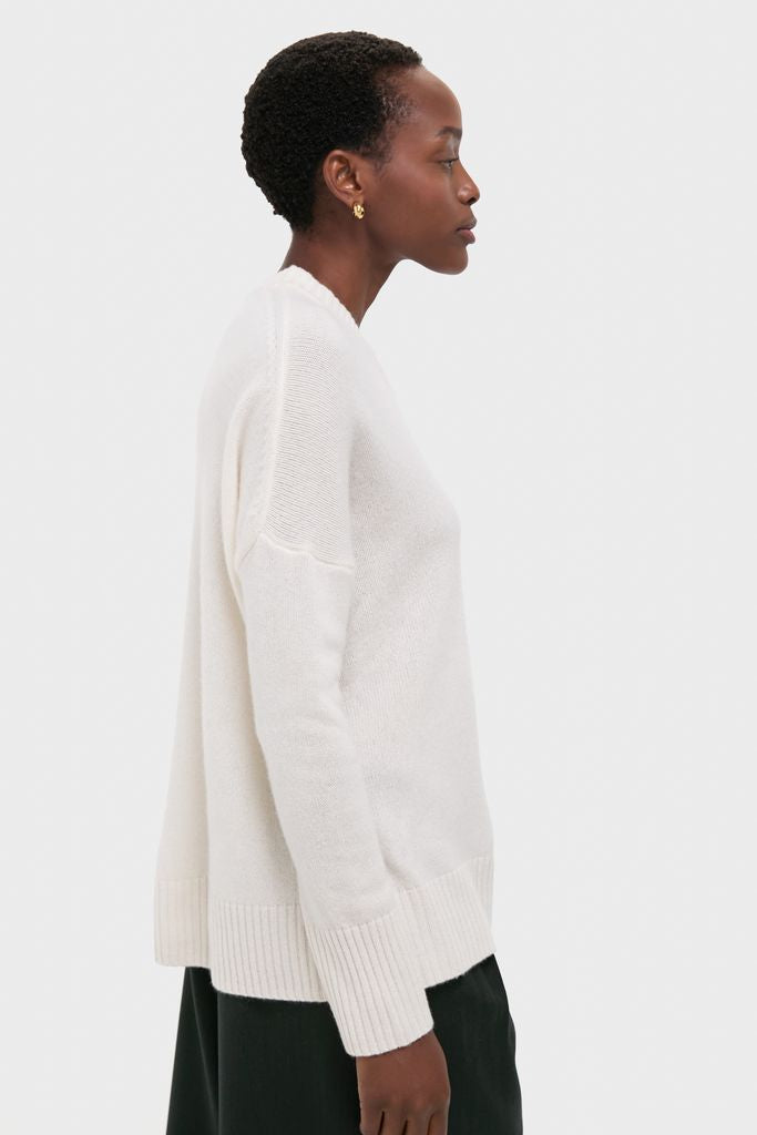 Person wearing the classic Ivory Cashmere Cassie V-Neck Sweater, featuring a relaxed fit and ribbed finishes, paired with dark trousers for an effortless, high-end look.