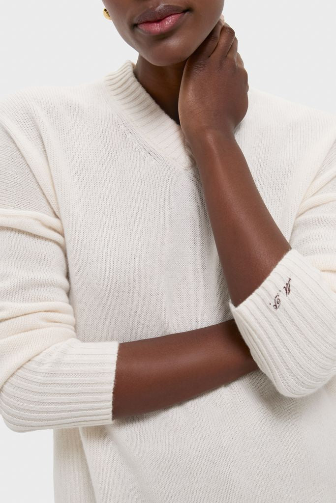 Ivory Cashmere Cassie V-Neck Sweater, classic and high-end, features a relaxed fit with ribbed cuffs, an embroidered detail, and effortless elegance for versatile styling.