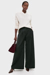 Woman wearing classic Ivory Cashmere Cassie V-Neck Sweater with relaxed fit, paired with wide-leg trousers and heels, holding a burgundy handbag, exuding effortless, high-end style.