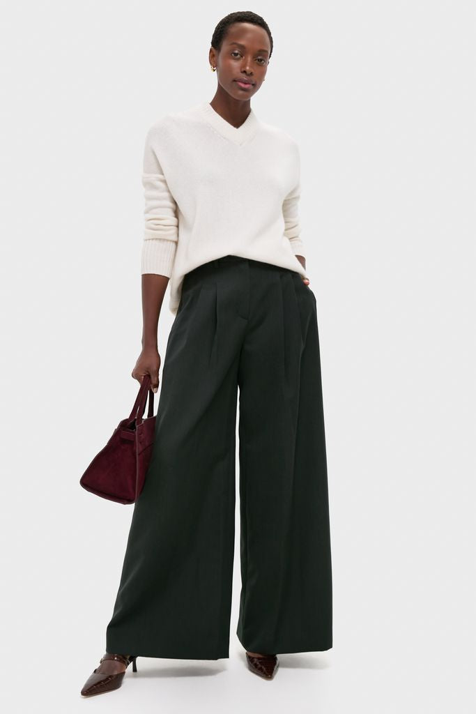 Woman wearing classic Ivory Cashmere Cassie V-Neck Sweater with relaxed fit, paired with wide-leg trousers and heels, holding a burgundy handbag, exuding effortless, high-end style.