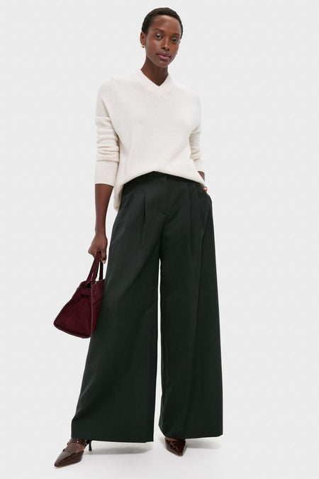 Woman wearing classic Ivory Cashmere Cassie V-Neck Sweater with relaxed fit, paired with wide-leg trousers and heels, holding a burgundy handbag, exuding effortless, high-end style.