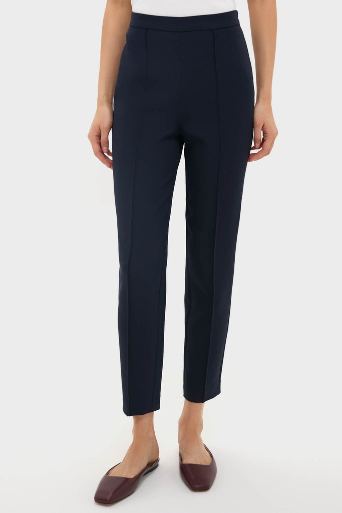 Navy Audrey Pants showcase a classic, effortless style with a slimming fit, pinched front seam, and side zipper, paired with burgundy mules for a high-end, fun look.