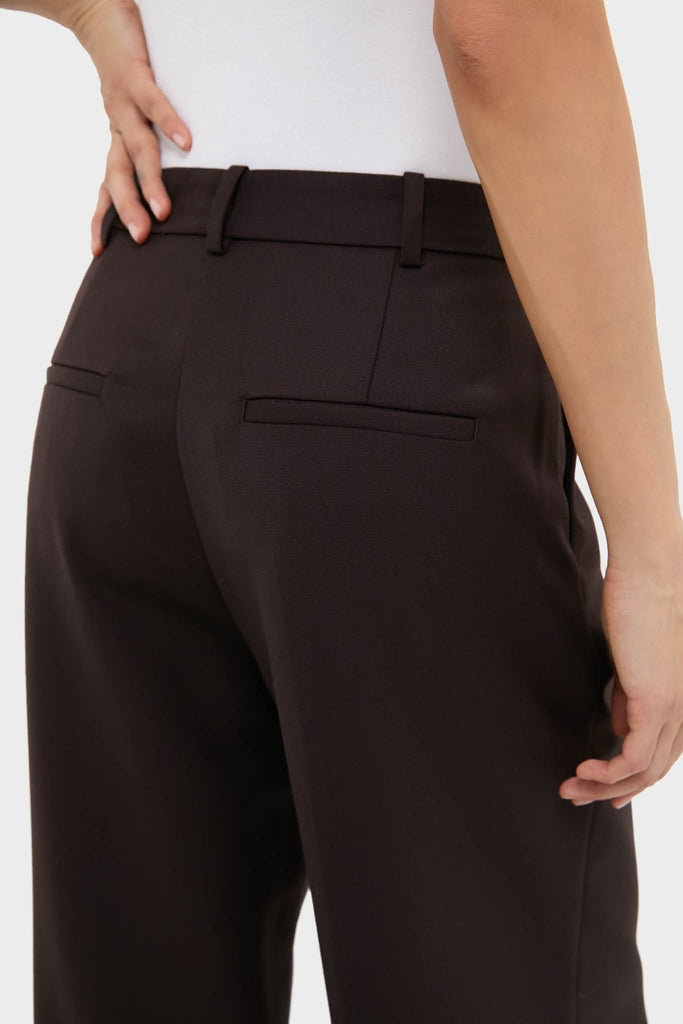 Person wearing classic Deep Brown Trent Trouser with tailored fit, slit back pockets, and relaxed leg, paired with a tucked-in white top for an effortless, high-end look.