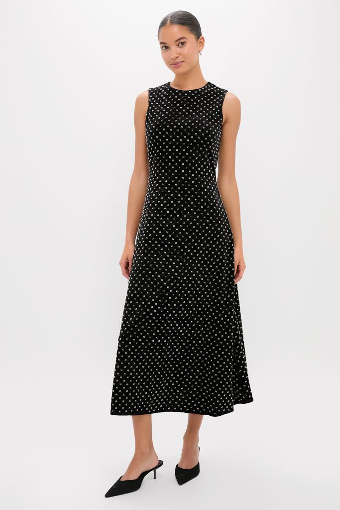 Woman in a classic Black Embellished Velvet Antonia Midi Dress, effortlessly styled with pointed-toe mules, embodying high-end, fun sophistication.