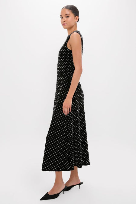 Model in profile wearing the Black Embellished Velvet Antonia Midi Dress, a classic, effortless look with a fun motif, paired with black pointed-toe mules.
