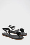 Black Flor Rose Wrap Sandals: classic thong-style with braided rosette detail, effortless flat footbed, and fun ankle wrap straps, embodying a high-end, stylish vibe.