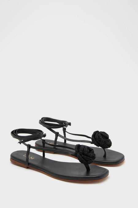 Black Flor Rose Wrap Sandals: classic thong-style with braided rosette detail, effortless flat footbed, and fun ankle wrap straps, embodying a high-end, stylish vibe.