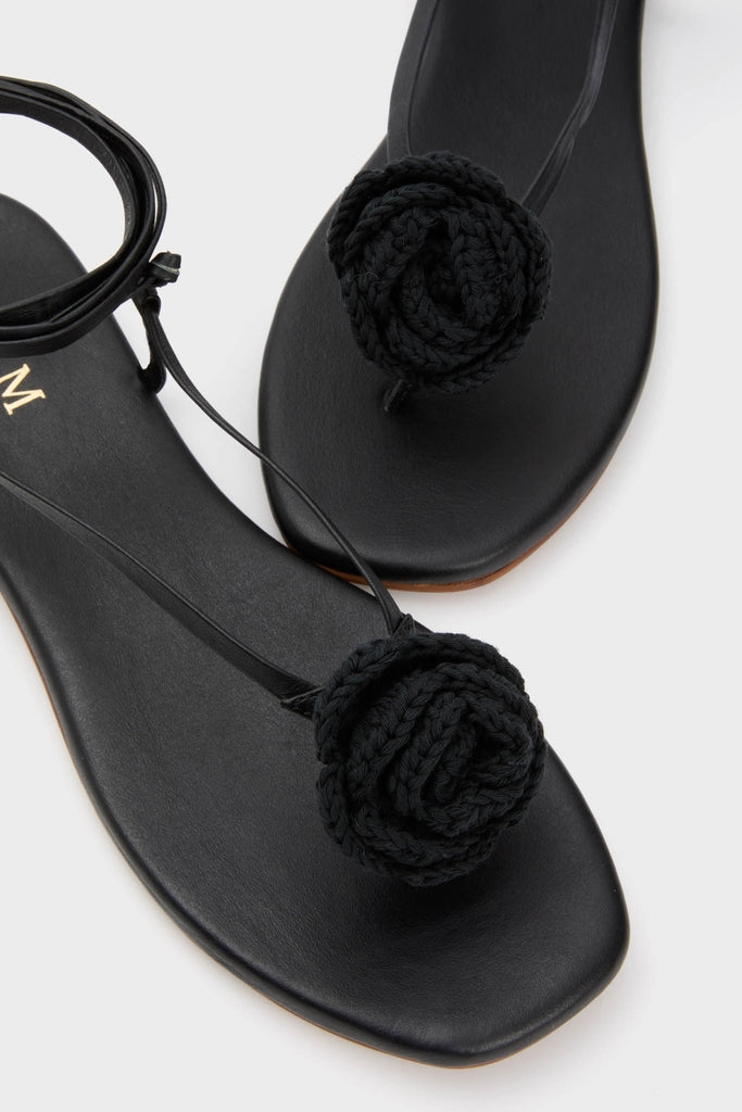 Black Flor Rose Wrap Sandals featuring classic thong design with a braided rose detail over the toe post and an effortless ankle strap, offering a fun, high-end look.