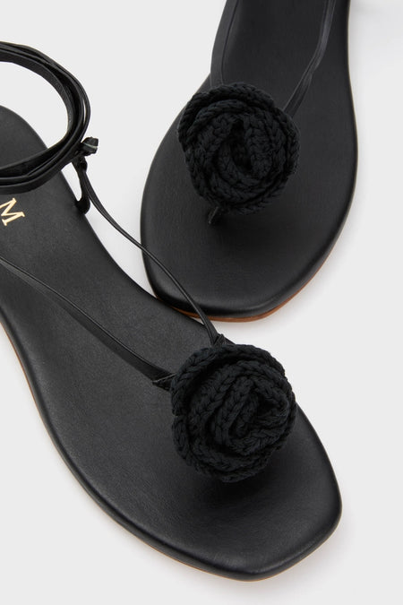 Black Flor Rose Wrap Sandals featuring classic thong design with a braided rose detail over the toe post and an effortless ankle strap, offering a fun, high-end look.