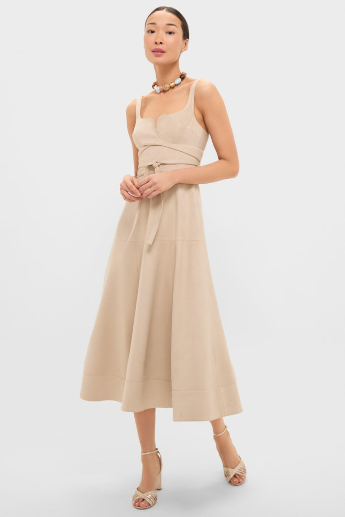 Woman in a classic, effortless Dune Suede Kendra Maxi Dress, featuring a square neckline, fitted bodice, and flared skirt, paired with fun, high-end accessories.