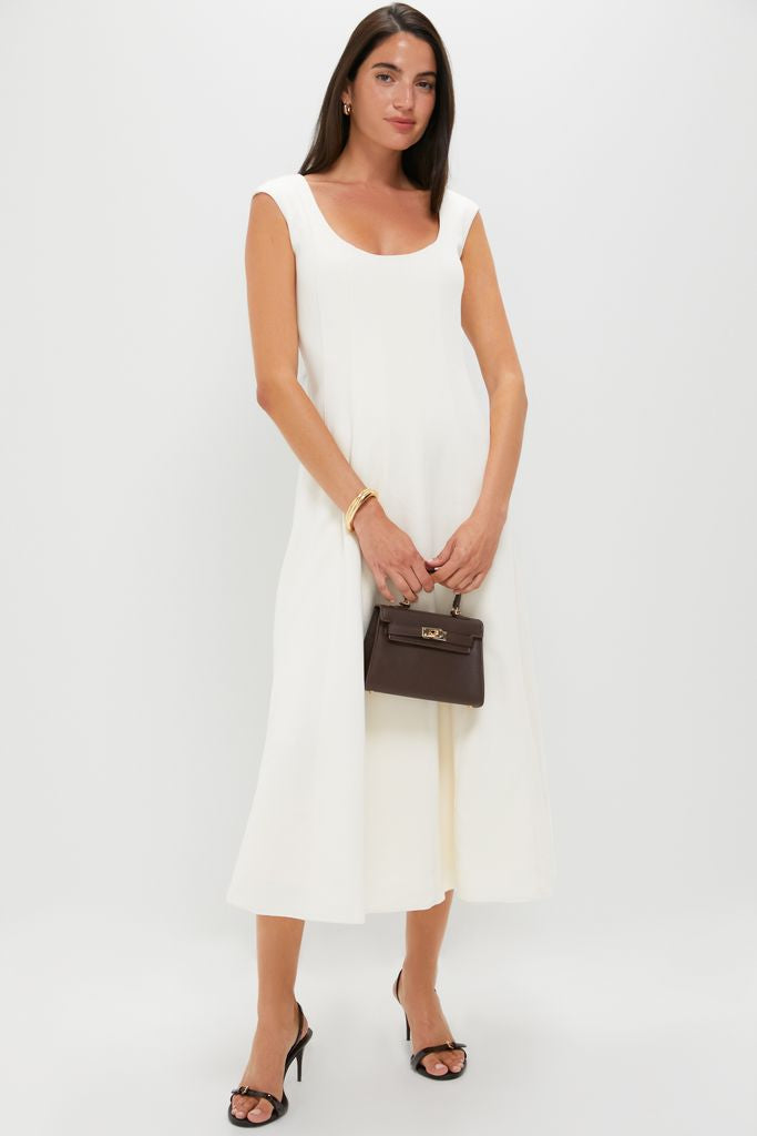 Model wears classic, high-end Maplewood Aurora Sling Mid Heels, featuring sleek straps and buckle details. Paired with an effortless white dress, exuding fun sophistication.
