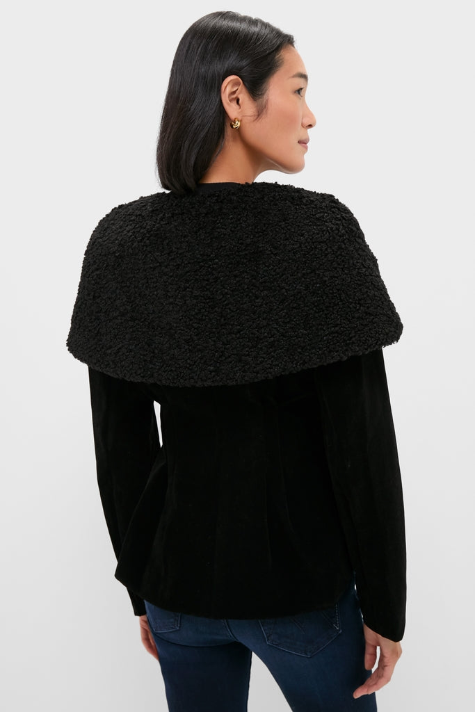 Black Geneva Jacket with a classic sherpa-style collar, effortlessly draped over shoulders. Paired with dark blue jeans, embodying a fun, high-end fashion for modern women.