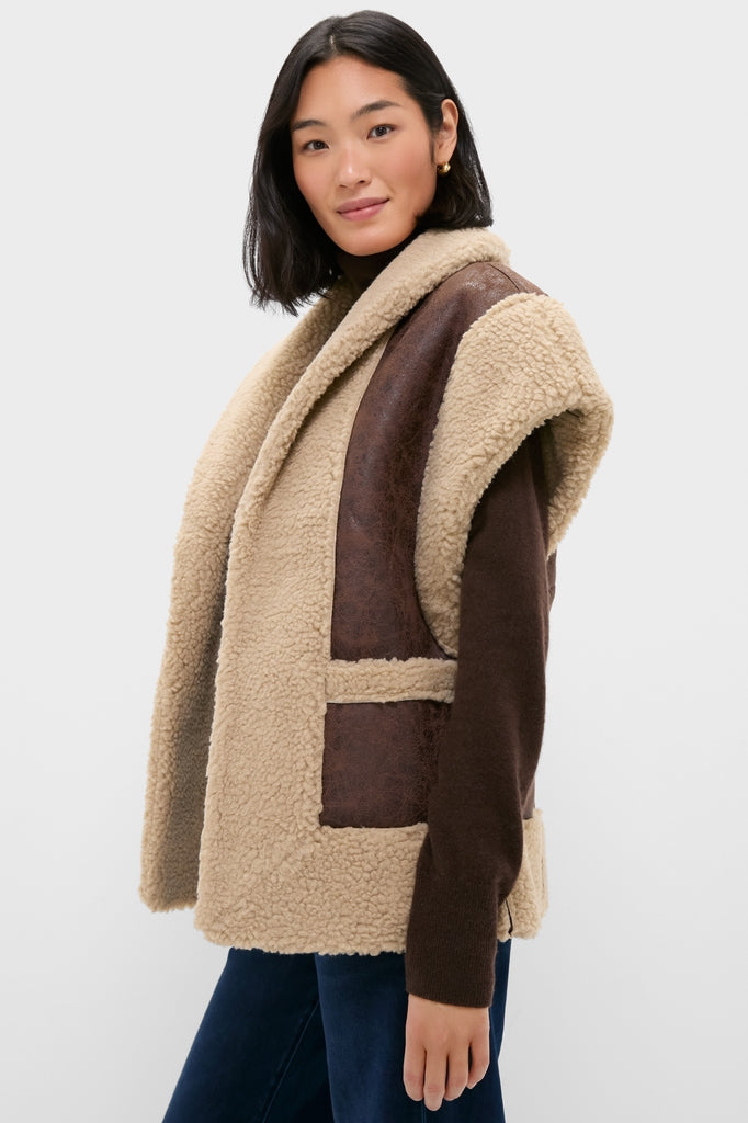 Woman models Brown Ace Faux Shearling Vest; classic, high-end design with teddy-fleece exterior and suede-like trim, layered effortlessly over dark top and jeans.