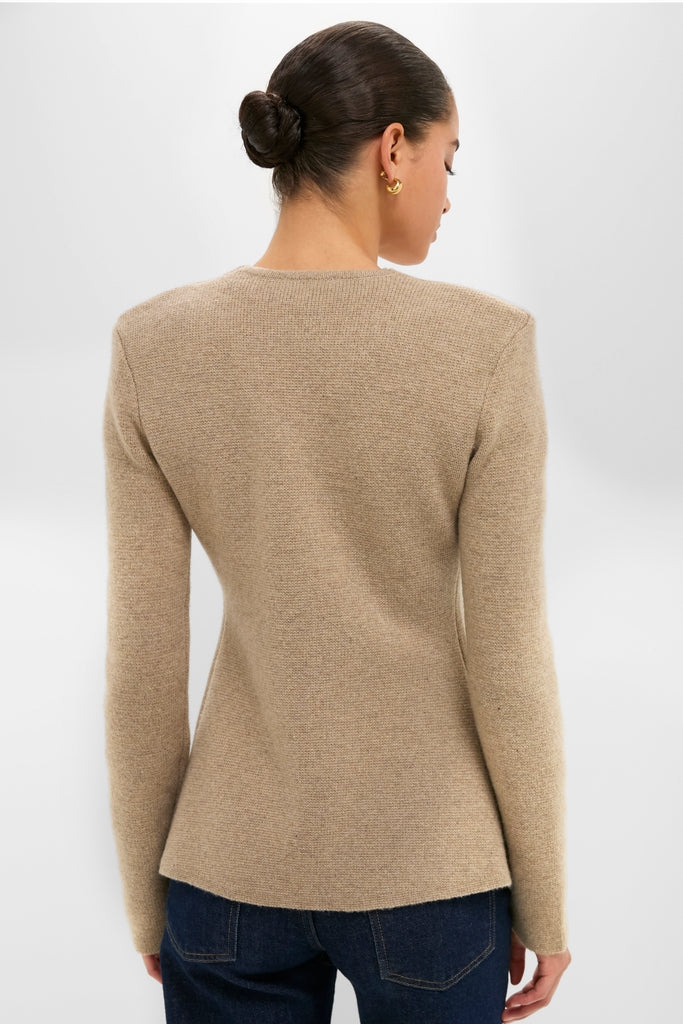 Back view of a woman in the classic Oatmeal Atleigh Sweater, showcasing its V-neckline and button closure, paired effortlessly with dark jeans for a high-end, fun look.