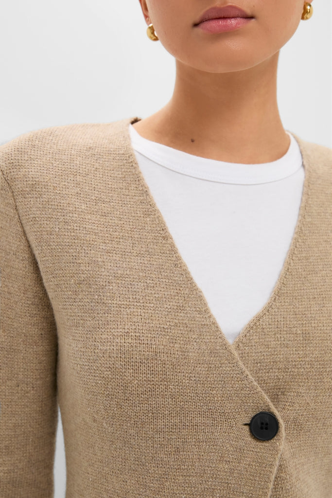 Close-up of a woman wearing the Oatmeal Atleigh Sweater, a classic V-neck cardigan with a button closure, small gold hoop earrings, showcasing effortless, high-end style.