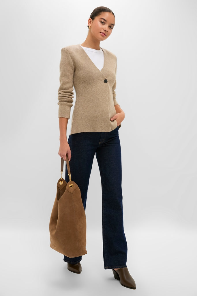 Model wearing the Oatmeal Atleigh Sweater, a classic V-neck cardigan with shoulder pads, paired effortlessly with jeans, ankle boots, and a slouchy tote for a high-end look.