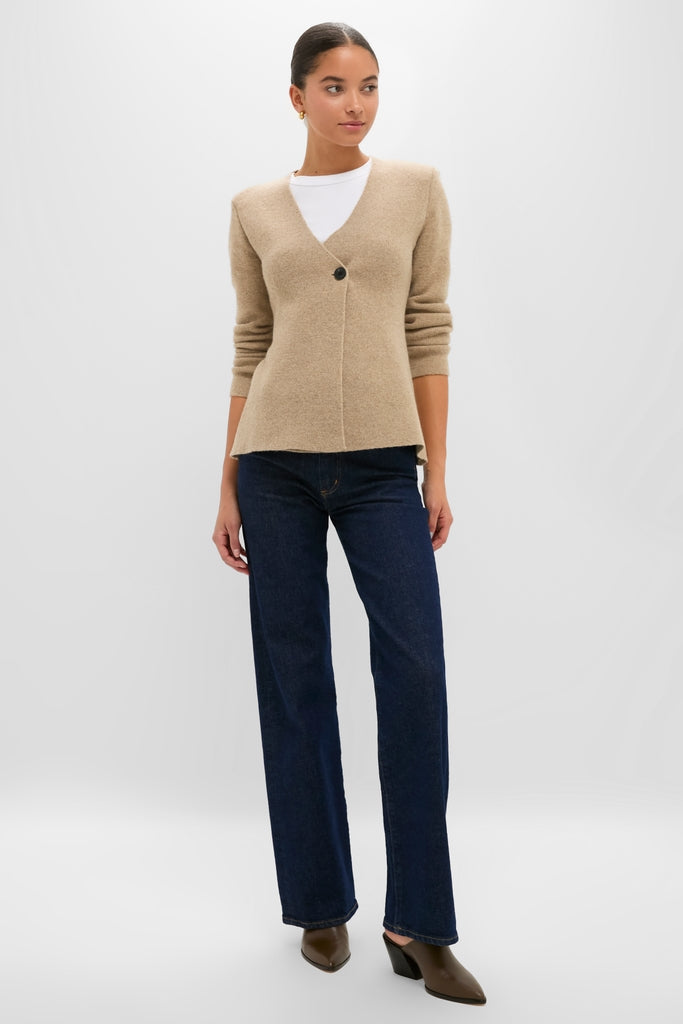 Woman models the Oatmeal Atleigh Sweater, a classic, effortless, high-end V-neck cardigan with a single button closure, paired with jeans and heeled mules.