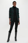 Woman in a classic Green Navy Multi Tartan Brushed Wool Blazer, exuding an effortless high-end style with a fitted black turtleneck and sleek black trousers.
