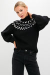 Young woman models the Black Marcie Fairisle Yoke Knit sweater, effortlessly pairing its classic turtleneck and balloon sleeves with dark jeans for a fun, high-end look.