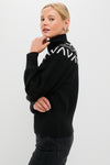 Model in profile wearing the classic Black Marcie Fairisle Yoke Knit sweater, featuring a chunky turtleneck, balloon sleeves, and chic geometric pattern, paired with dark jeans.
