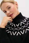 Young woman in a chunky black Marcie Fairisle Yoke Knit sweater, showcasing its classic turtleneck and balloon sleeves, effortlessly combining fun and high-end style.