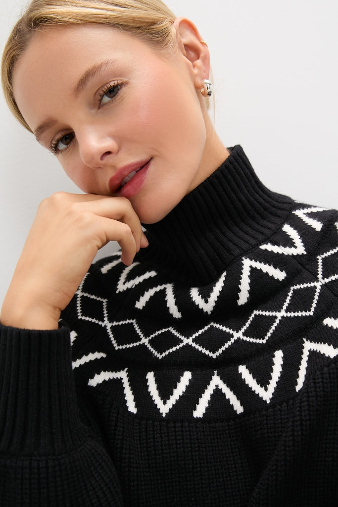 Young woman in a chunky black Marcie Fairisle Yoke Knit sweater, showcasing its classic turtleneck and balloon sleeves, effortlessly combining fun and high-end style.