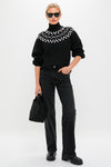 Woman in classic Black Marcie Fairisle Yoke Knit sweater, styled effortlessly with straight-leg jeans and platform boots, embodies high-end winter fashion with a fun geometric pattern.